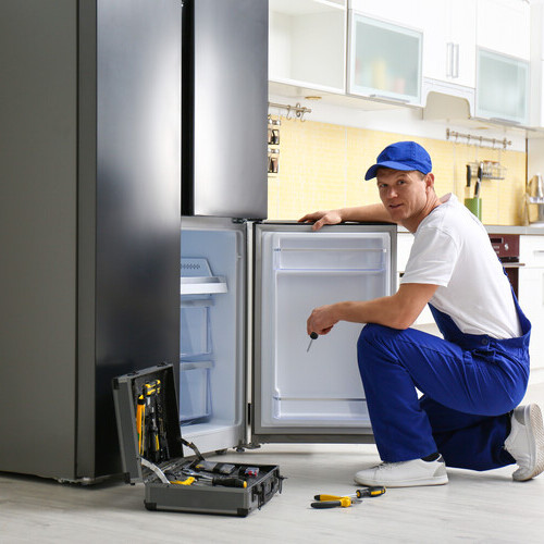 Technician repairing a modern refrigerator ice maker assembly