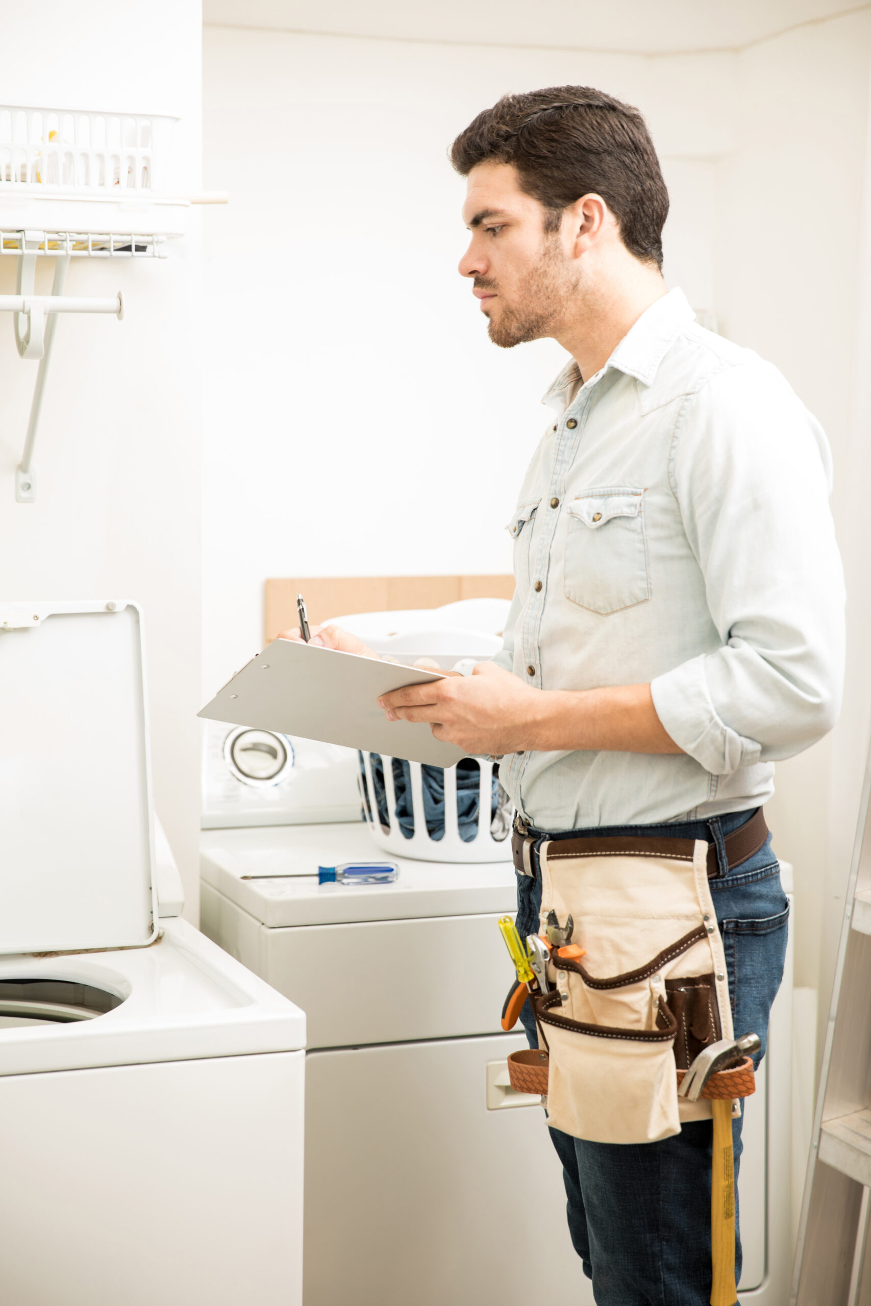 Appliance repair technician inspecting a household appliance and preparing a repair assessment